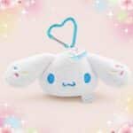 Une peluche Cinnamoroll porte-clés avec mousqueton blanche et douce, avec de grandes oreilles et un mousqueton bleu en forme de cœur, sur fond pastel avec des étoiles.