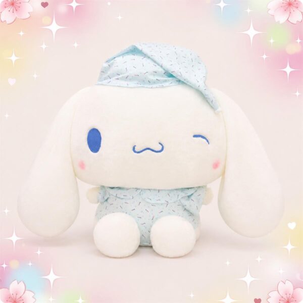 Une peluche Cinnamoroll en tenue de nuit bleue pastel, avec un petit bonnet assorti, assise sur un fond rose doux avec des étoiles et des fleurs.