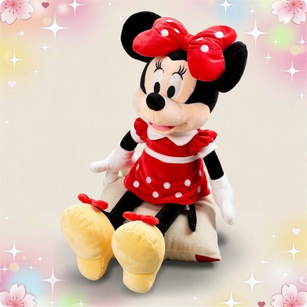 Une peluche Minnie grand format assise en robe rouge à pois blancs, avec un grand nœud rouge, sur un fond pastel décoré d’étoiles et de cœurs.