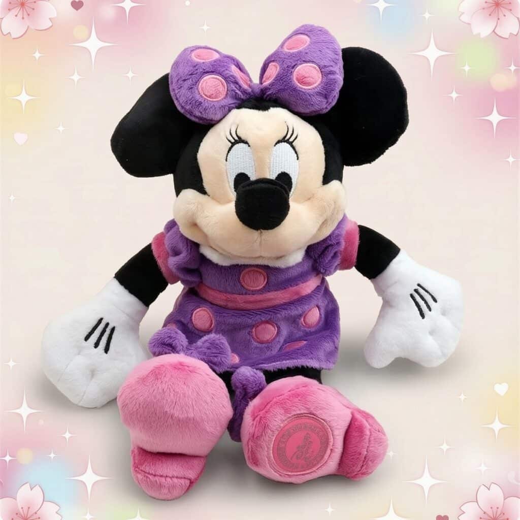 Une peluche Minnie portant une robe violette, assise sur un fond rose décoré de petits cœurs et d’étoiles brillantes.