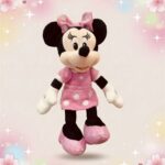 Une peluche Minnie dans sa robe rose à pois, avec un grand nœud rose et des chaussures roses, sur un fond doux avec des étoiles et des cœurs.