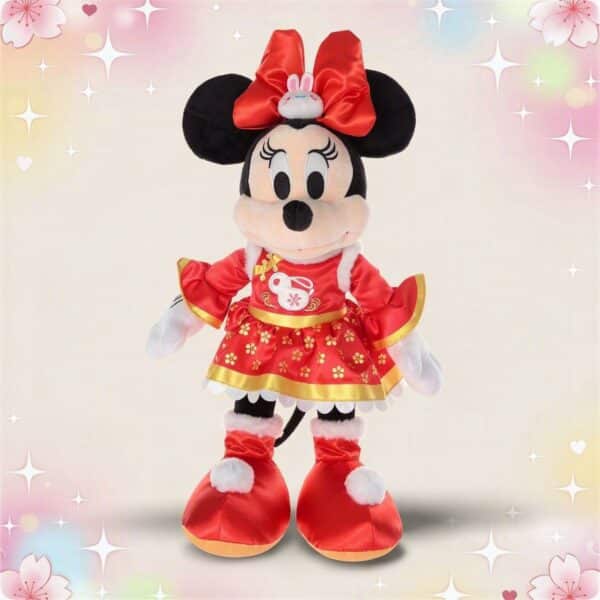 Une peluche Minnie en tenue traditionnelle asiatique rouge, debout sur fond clair avec des motifs brillants et des fleurs, portant une robe rouge ornée d’or et un grand nœud rouge.