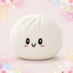 Une peluche Squishmallow en forme de gros ravioli blanche, ronde et moelleuse, avec un petit visage souriant, sur un fond rose pastel décoré d’étoiles et de fleurs.