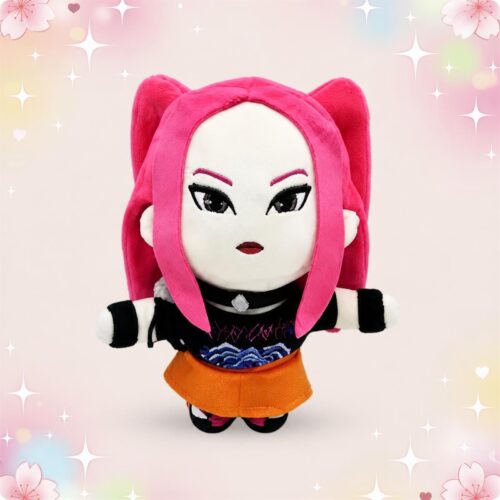 Une peluche Kpop Demon Hunters Mira aux cheveux roses, avec une tenue noire et orange, sur un fond pastel décoré d’étoiles et de petits cœurs.
