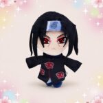 Une peluche Naruto Itachi aux yeux Sharingan et manteau Akatsuki, avec de grands yeux rouges, des cheveux noirs et un fond rose décoré d’étoiles et de cœurs.
