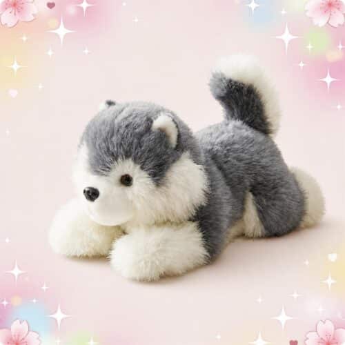 Une peluche chien Malamute de l'Alaska grise et blanche, couchée sur un fond rose décoré de petites étoiles et fleurs.