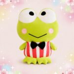 Une peluche grenouille portant un noeud papillon, avec de grands yeux ronds, un ventre rayé rouge et blanc, sur un fond rose décoré de petites étoiles et de cœurs.