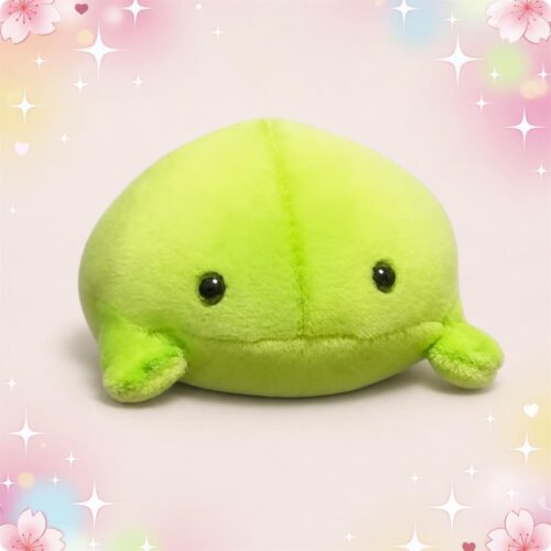 Une peluche grenouille ronde petit format verte et toute douce, avec de petits yeux noirs, posée sur un fond pastel décoré de fleurs et d’étoiles.