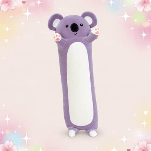 Une peluche Koala au format long coussin de corps violette, avec un ventre blanc et de petites pattes, sur fond pastel décoré d’étoiles et de cœurs.