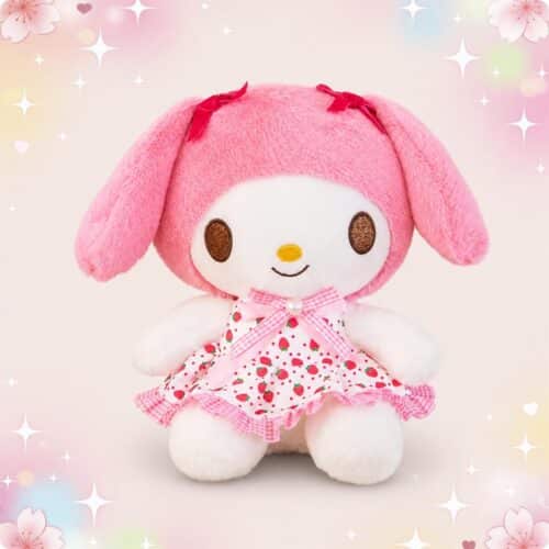 Une peluche My Melody portant une robe à imprimé fraises, avec de longues oreilles roses et un fond pastel décoré d’étoiles et de fleurs.