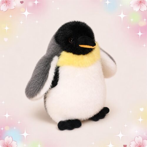 Une peluche pingouin à cou jaune toute douce, debout avec le ventre blanc, le dos gris, la tête noire et le bec jaune, sur un fond pastel décoré de cœurs et d’étoiles.