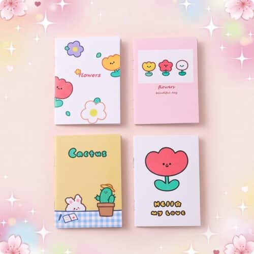 Quatre cahiers kawaii A5 à motif fleurs, avec des dessins mignons de fleurs, cactus et couleurs pastel sur un fond rose doux.