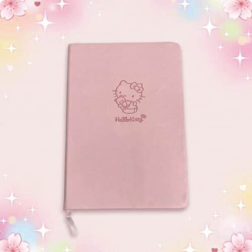 Un carnet kawaii rose Hello Kitty à la couverture rose poudré, avec un petit dessin Hello Kitty au centre et un fond doux décoré d’étoiles et de fleurs.