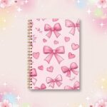 Un carnet kawaii à spirales noeuds roses et coeurs rose, avec une couverture décorée de grands nœuds et de petits cœurs, posé sur un fond doux et scintillant.