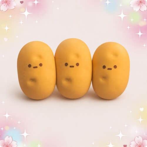 Trois gommes kawaii sculptées en forme de pomme de terre, jaunes et toutes mignonnes, posées côte à côte sur un fond rose décoré d’étoiles et de petits cœurs.