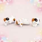 Un lot de 3 figurines kawaii chats en résine, trois petits chats blancs et tachetés posés sur un fond rose doux avec des étoiles et des fleurs.