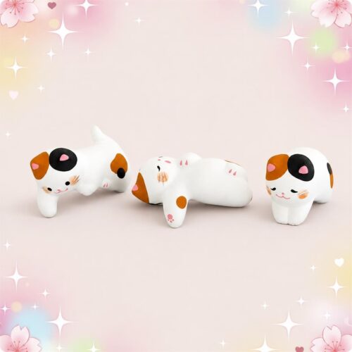 Un lot de 3 figurines kawaii chats en résine, trois petits chats blancs et tachetés posés sur un fond rose doux avec des étoiles et des fleurs.