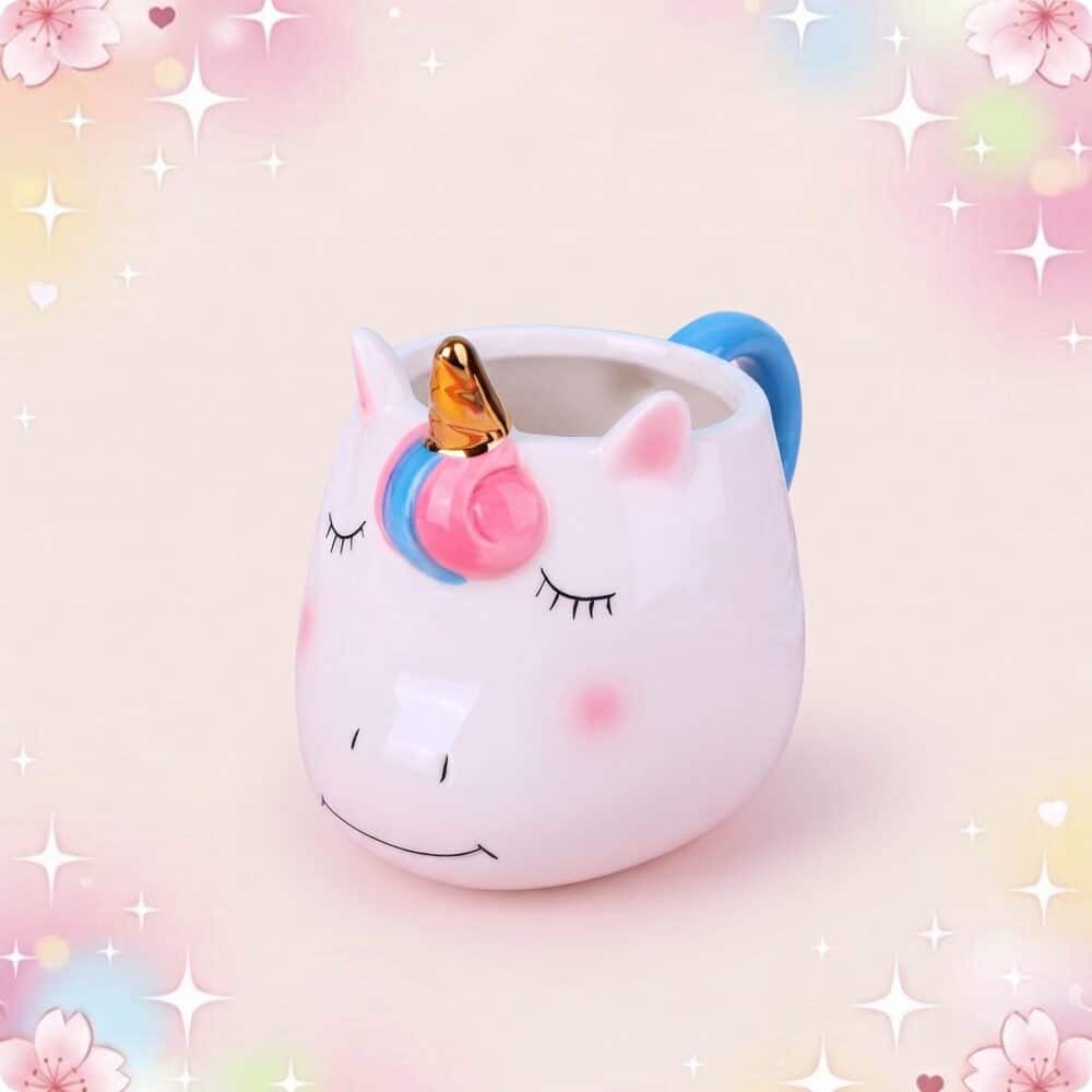 Un mug kawaii licorne en céramique blanc, avec une tête de licorne, une corne dorée et une anse bleue, sur un fond rose doux plein d’étoiles.