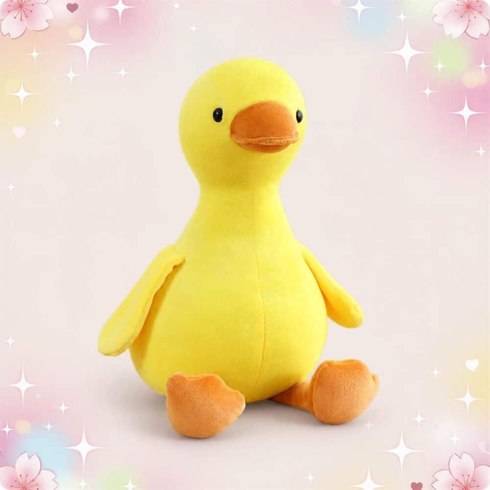 Une peluche canard adorable assis jaune, avec un bec et des pattes orange, posée sur un fond doux décoré d’étoiles et de cœurs.