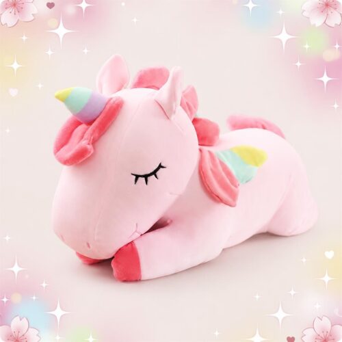 Une peluche licorne endormie grand format rose, avec une corne arc-en-ciel et des yeux fermés, posée sur un fond doux et décoré d’étoiles.