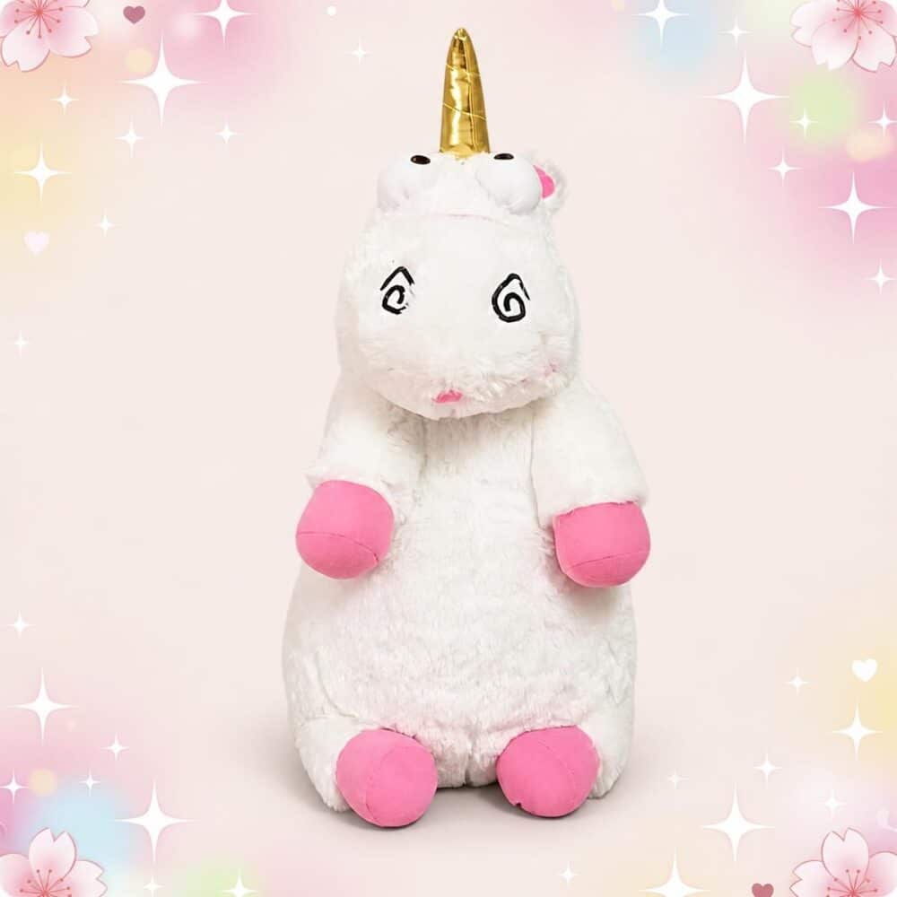 Une peluche licorne Moi Moche et Méchant blanche avec corne dorée, yeux en spirale et pattes roses, posée sur un fond rose décoré d’étoiles brillantes.