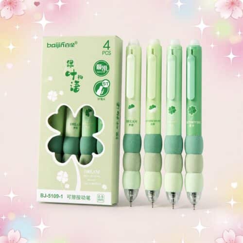 Un lot de 4 Stylo Kawaii design trèfle à quatre feuilles verts, avec des gommes épaisses et une boîte assortie sur fond rose décoré de cœurs et d’étoiles.