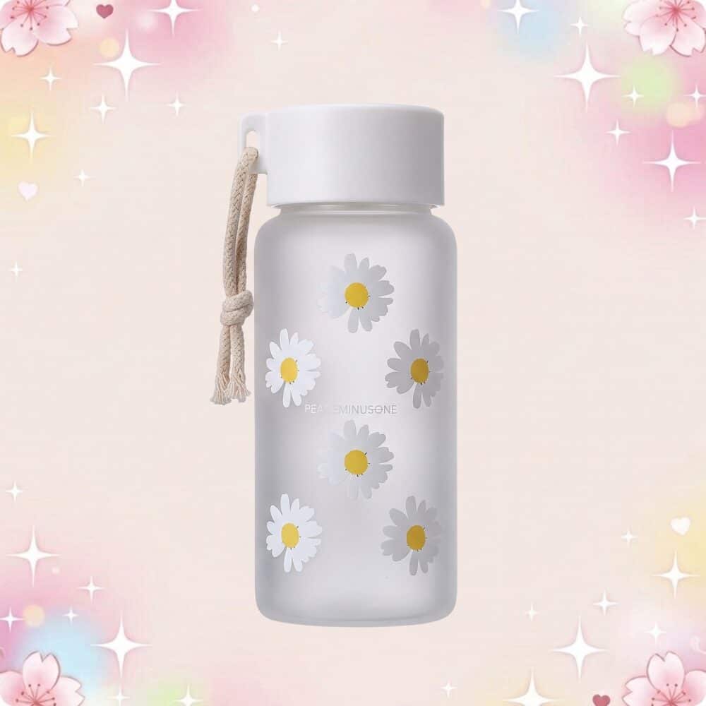 Une gourde kawaii transparente à motif marguerite grise avec un cordon, posée sur un fond rose pastel décoré de petites étoiles et fleurs.