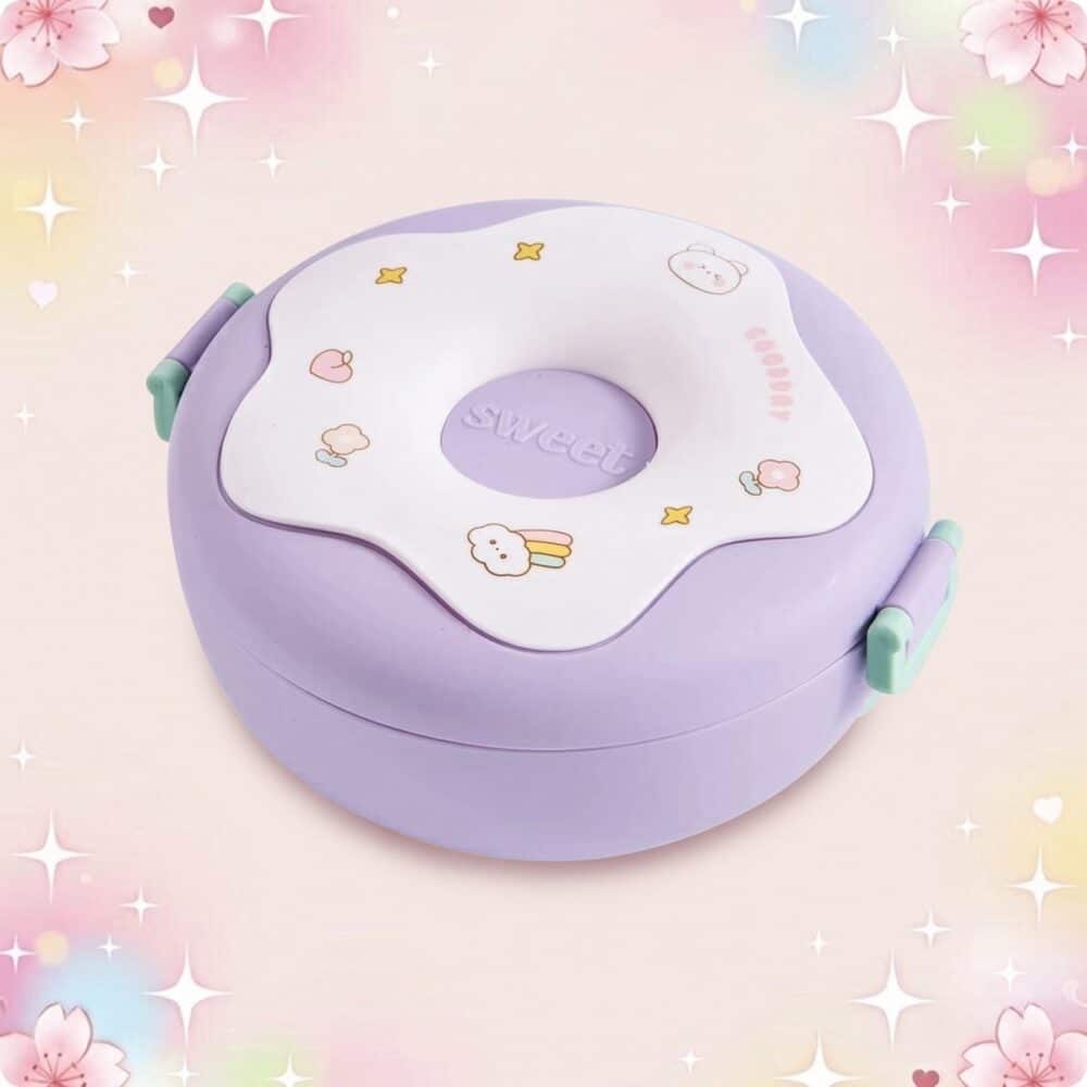 Une lunchbox kawaii ronde en forme de donut violette avec couvercle blanc décoré de petits motifs, posée sur un fond pastel scintillant.