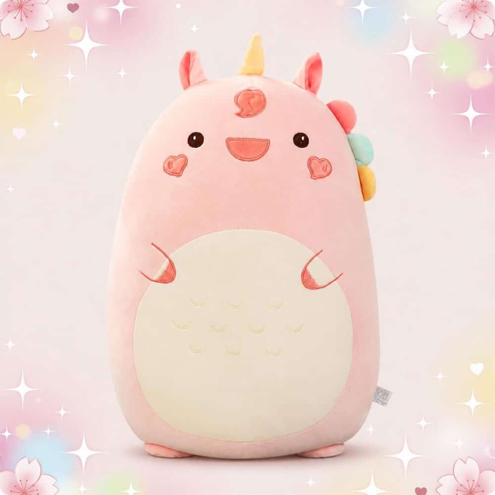 Une peluche animal kawaii licorne squishmallow rose, toute douce et ronde, avec une petite corne jaune, un visage souriant et un fond pastel avec des étoiles et des cœurs.