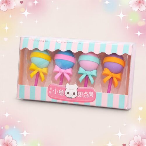 Une boîte de Gomme Kawaii imitant une sucette bien ronde lot de 3 boites, avec quatre gommes colorées en forme de sucette à ruban, sur un fond rose décoré d’étoiles.