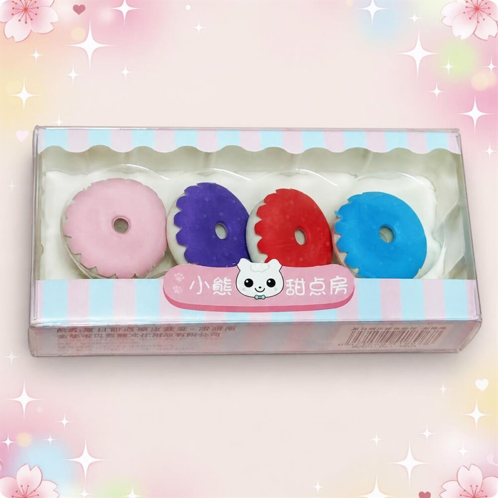 Une boîte de Gomme Kawaii ressemblant à un donut lot de 3 boites, avec quatre gommes rondes rose, violette, rouge et bleue sur un fond pastel.