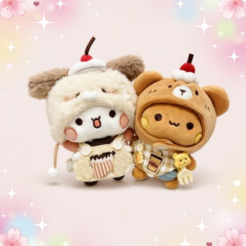 Une main tient deux peluches Bubu et Dudu en porte clés gourmands, avec de petits chapeaux à dessert et un fond rose décoré de cœurs et d’étoiles.