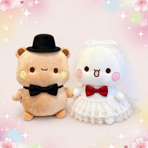 Une peluche Bubu et Dudu en tenue de jeunes mariés, avec un ours beige en chapeau noir et nœud papillon noir, et une ourse blanche en voile et robe de mariée.