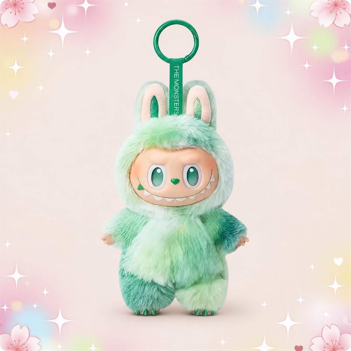 Un porte-clé peluche Labubu coloré vert menthe, en forme de petit monstre tout doux avec grandes oreilles, suspendu à un anneau vert, sur fond pastel décoré d’étoiles et de cœurs.