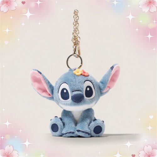 Un porte-clé peluche Stitch bleu, avec de grandes oreilles roses et une petite chaîne métallique, posé sur un fond pastel décoré d’étoiles et de fleurs.
