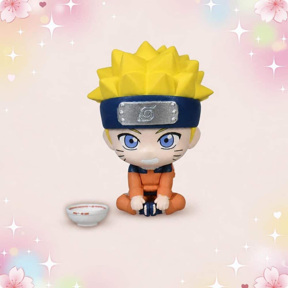 Une figurine Gachapon Naruto montrant un petit personnage blond assis en tenue orange avec un bandeau bleu, avec un petit bol à côté, sur un fond rose décoré d’étoiles et de cœurs.