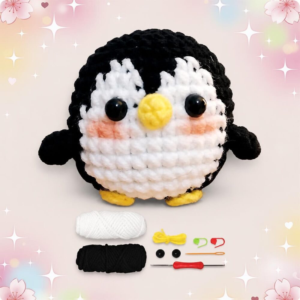 Un kit amigurumi pingouin avec un petit pingouin crocheté, des pelotes de laine blanche et noire, des yeux, un crochet et des accessoires sur fond pastel décoré.