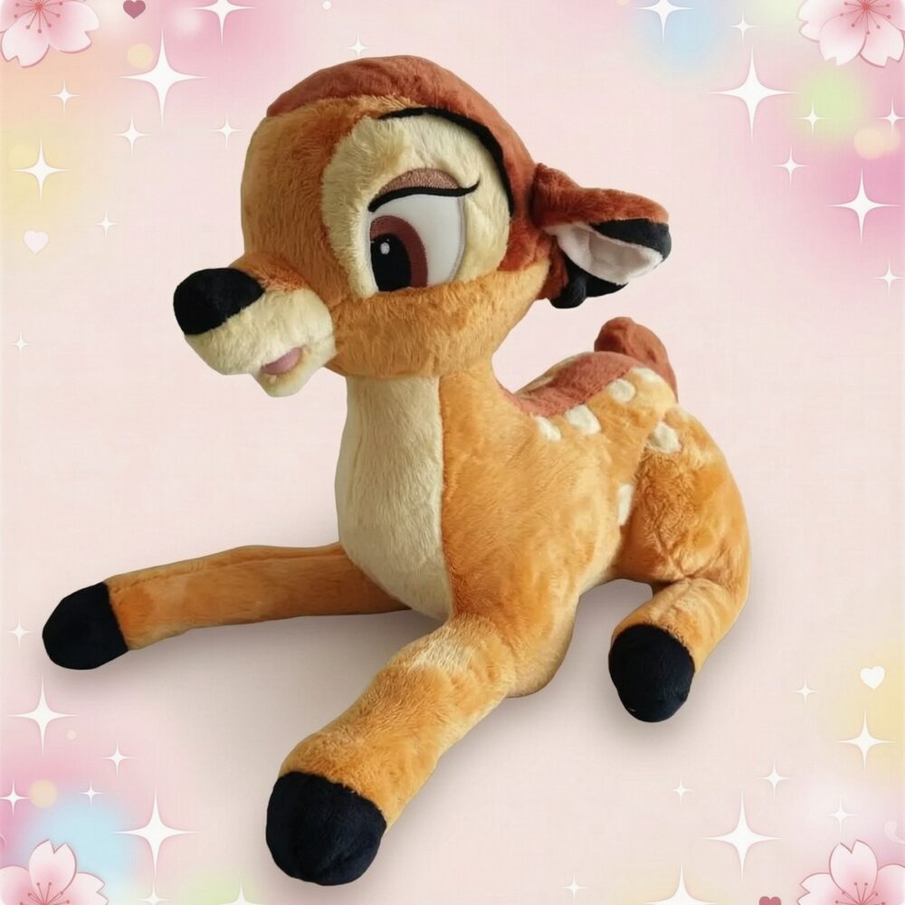Une peluche Disney Bambi en forme de petit faon brun et beige, avec de grandes oreilles et de longues pattes, posée sur un fond rose décoré d’étoiles et de fleurs.