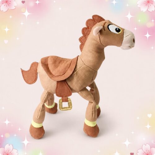 Une peluche Disney Pile-Poil de Toy Story en forme de cheval marron, debout sur un fond rose doux avec des petites étoiles et des fleurs.