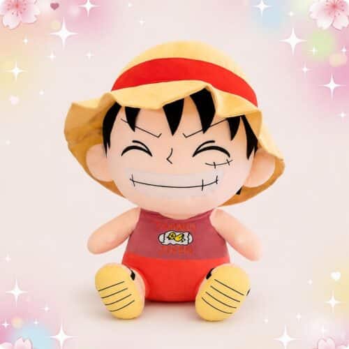 Une grande peluche manga Luffy grand format souriante, assise avec un chapeau de paille rouge et jaune, sur un fond rose décoré d’étoiles et de cœurs.