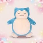 Une peluche Pokemon Ronflex bleue et blanche, avec un gros ventre rond, posée sur un fond doux avec des étoiles et des fleurs pastel.