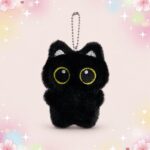 Un porte-clé peluche chat noir kawaii tout doux, avec de grandes yeux ronds jaunes et une petite chaîne en métal, sur fond rose pastel décoré d’étoiles.