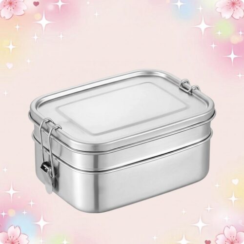 Un bento kawaii en acier inoxydable argenté avec couvercle et fermoir, posé sur un fond rose décoré de petites étoiles et fleurs.
