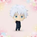 Une figurine gachapon Satoru Gojo aux cheveux blancs et aux yeux bleus, debout sur un fond rose pastel décoré de cœurs et d’étoiles.
