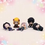 Un lot de 5 figurines Gachapon piliers de Demon Slayer montrant cinq petits personnages chibi allongés ou assis, avec des cheveux noirs, jaunes et blancs, sur un fond doux et pastel.