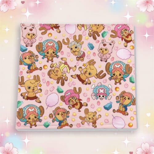Un plaid kawaii chopper de one piece rose avec des petits personnages mignons et des motifs colorés, posé sur un fond doux et pastel.