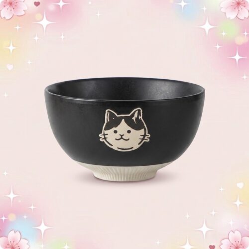 Un bol noir de vaisselle kawaii bol motif animaux mignons, avec un visage de chat blanc et noir, posé sur un fond rose pastel avec des étoiles et des fleurs.