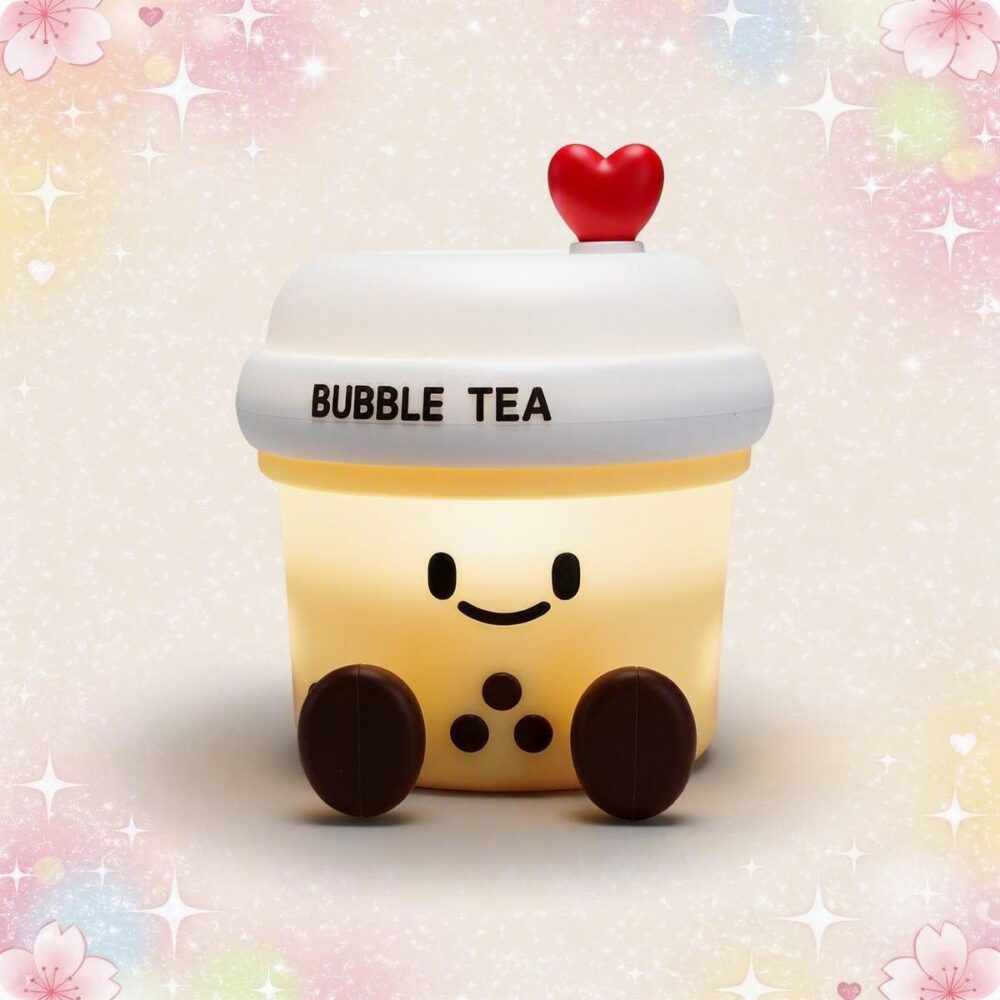 Une veilleuse Kawaii bubble tea aux lumières chaudes en forme de gobelet souriant, avec un petit cœur rouge sur le dessus, sur fond doux et pastel.