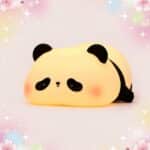 Une Veilleuse Kawaii en panda avec sa minuterie intégrée en forme de petit panda lumineux, posée sur un fond rose doux avec des petites étoiles.