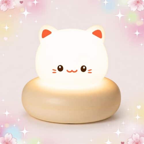 Une Veilleuse Kawaii en chat à la clarté modulable en forme de chat blanc qui brille doucement, posée sur un fond rose décoré d’étoiles.